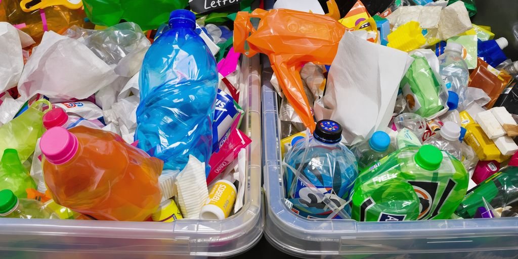 Des mains triant des déchets colorés dans des bacs.