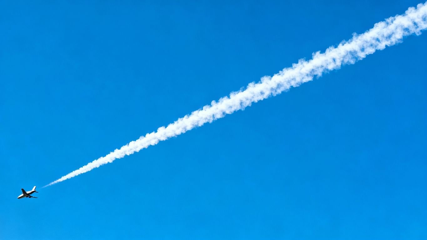 Avion laissant une traînée blanche dans le ciel bleu.